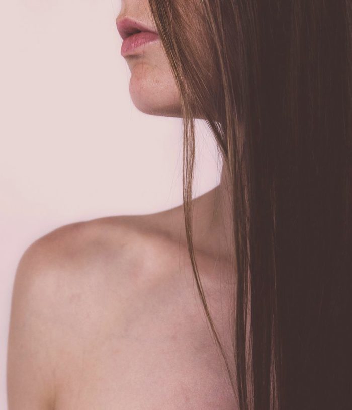 Long, glass-smooth hair falling over a bare shoulder